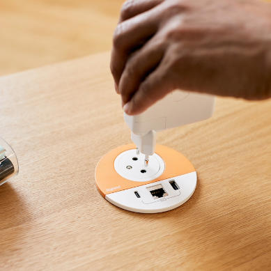 A charger is being plugged into a soft orange and white Disq-socket.